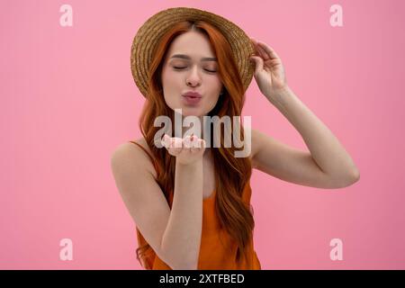 Mignonne jeune femme en chapeau de paille envoyant un baiser aérien Banque D'Images