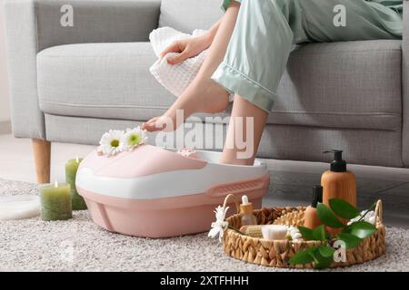 Femme avec des fournitures de spa en utilisant le bain de pied de massage à la maison Banque D'Images