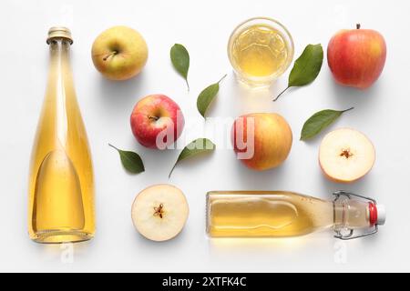 Composition avec des fruits, des bouteilles et un verre de cidre de pomme frais sur fond blanc Banque D'Images
