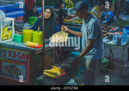 Balikpapan, Indonésie - 15 juin 2024. il est un vendeur de nourriture de rue qui torréfie quelques cors pour ses clients. Banque D'Images