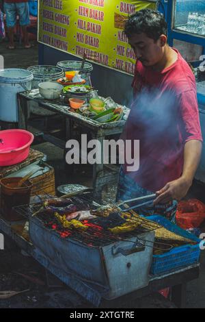 Balikpapan, Indonésie - 15 juin 2024. il est un vendeur de nourriture de rue qui grillent des poulets pour ses clients. Banque D'Images