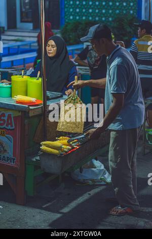 Balikpapan, Indonésie - 15 juin 2024. il est un vendeur de nourriture de rue qui torréfie quelques cors pour ses clients. Banque D'Images