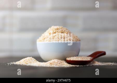 Psyllium Husk (Isabgol) dans un bol avec une cuillère en bois sur un fond noir Banque D'Images