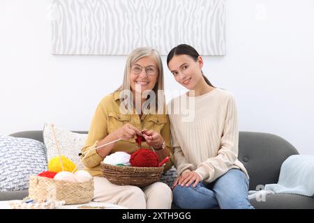Heureuse mère et fille avec des écheveaux de fil sur le canapé à la maison Banque D'Images