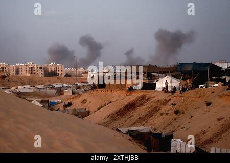 De la fumée s'élève à proximité de la zone des tours Hamad, à l'Ouest de Khan Younis, voyage à Gaza, 14 août 2024. Des avions militaires Iraeli ont attaqué la ville de Hamad alors que l'artillerie explosait des bâtiments résidentiels à Khan Younis, dans le sud de la bande de Gaza, après que des dizaines de personnes eurent été tuées dans des attaques à travers le territoire palestinien au cours des 24 heures précédentes. Les États-Unis et Israël envoient des délégations au Qatar pour des pourparlers de cessez-le-feu qui doivent commencer plus tard aujourd’hui, tandis que le Hamas a déclaré aux médiateurs qu’il était prêt à se réunir après les discussions pour déterminer s’il y avait une réponse sérieuse d’Israël aux propositions de trêve. Photo de Ramez Habboub/ Banque D'Images