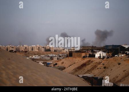 De la fumée s'élève à proximité de la zone des tours Hamad, à l'Ouest de Khan Younis, voyage à Gaza, 14 août 2024. Des avions militaires Iraeli ont attaqué la ville de Hamad alors que l'artillerie explosait des bâtiments résidentiels à Khan Younis, dans le sud de la bande de Gaza, après que des dizaines de personnes eurent été tuées dans des attaques à travers le territoire palestinien au cours des 24 heures précédentes. Les États-Unis et Israël envoient des délégations au Qatar pour des pourparlers de cessez-le-feu qui doivent commencer plus tard aujourd’hui, tandis que le Hamas a déclaré aux médiateurs qu’il était prêt à se réunir après les discussions pour déterminer s’il y avait une réponse sérieuse d’Israël aux propositions de trêve. Photo de Ramez Habboub/ Banque D'Images