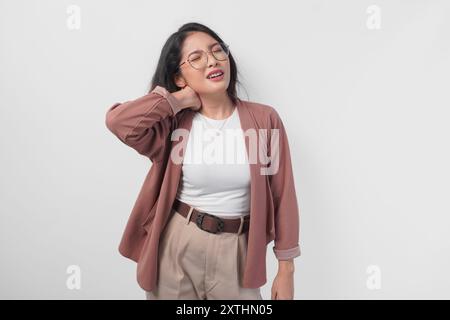 Femme asiatique fatiguée portant des lunettes souffrant de douleur, spasme musculaire sur le fond blanc isolé du cou. Banque D'Images