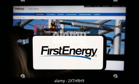 Personne tenant un téléphone portable avec le logo de la société US de services publics d'électricité FirstEnergy Corp. en face de la page Web de l'entreprise. Concentrez-vous sur l'affichage du téléphone. Banque D'Images