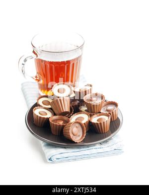 Pralines sucrées. Truffes au chocolat et tasse de thé isolé sur un fond blanc. Banque D'Images