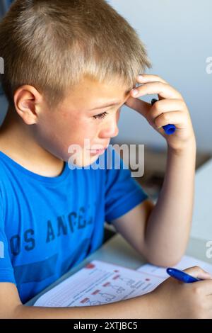 Un garçon portant un T-shirt bleu pleure à l'école Banque D'Images
