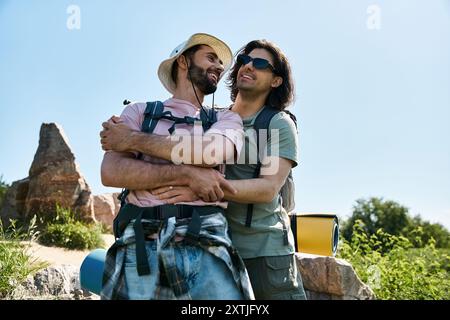 Un couple gay, profitant d'une randonnée estivale ensemble dans la nature. Ils marchent à travers la nature sauvage et s'embrassent. Banque D'Images