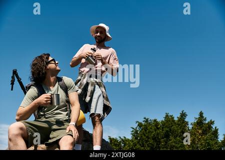 Deux jeunes hommes, un couple gay, font une randonnée dans la nature sauvage par une journée ensoleillée. Ils apprécient le plein air et les uns les autres compagnie. Banque D'Images