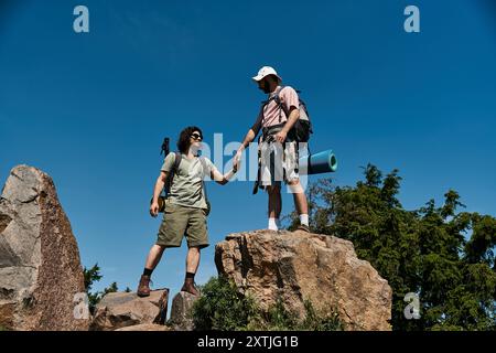 Un jeune couple gay faisant de la randonnée ensemble dans la nature sauvage estivale, profitant du plein air et les uns des autres en compagnie. Banque D'Images