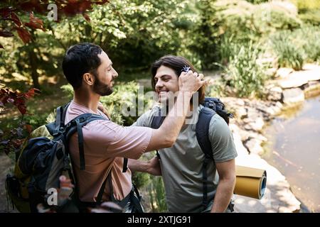 Un jeune couple gay fait des randonnées à travers une forêt luxuriante en été, profitant du plein air et de la compagnie des autres. Banque D'Images