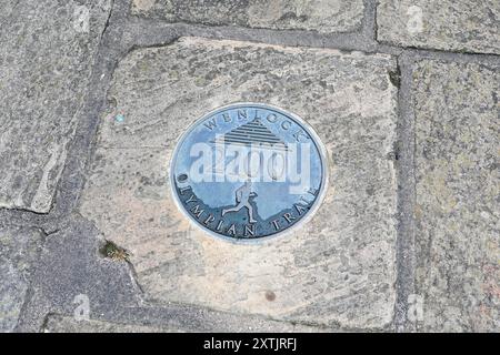 Un marqueur dans le trottoir pour le sentier Olympian à Much Wenlock, une ville de marché et paroisse dans le Shropshire, Angleterre, Royaume-Uni Banque D'Images