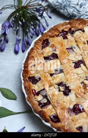 Tarte au treillis de myrtille fraîchement cuite sur une table. Belle croûte dorée en gros plan. Gâteau rond sucré maison. Fond gris clair avec espace de copie Banque D'Images