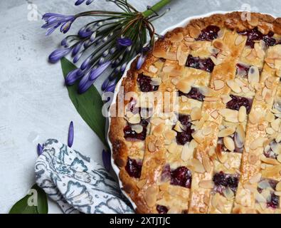 Tarte au treillis de myrtille fraîchement cuite sur une table. Belle croûte dorée en gros plan. Gâteau rond sucré maison. Fond gris clair avec espace de copie Banque D'Images
