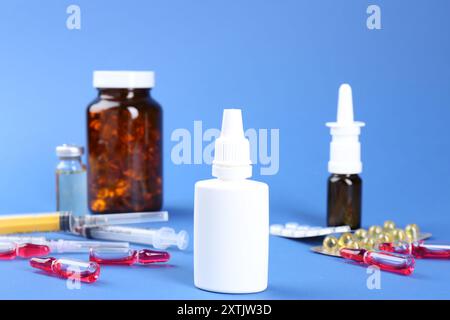 Pharmacien. Bouteilles de gouttes médicales, ampoules de pilules et seringues sur fond bleu Banque D'Images