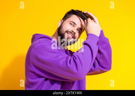 Photo de beau homme soigné attrayant porter un peigne de vêtements élégants violet espace vide isolé sur fond de couleur jaune Banque D'Images