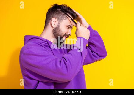 Photo de l'homme macho soigné attrayant porter un peigne de cheveux de brosse de vêtements élégant violet isolé sur fond de couleur jaune Banque D'Images