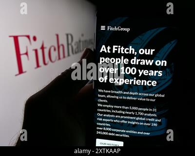 Personne tenant un smartphone avec le site Web de l'agence de notation de crédit américaine Fitch Ratings Inc devant le logo de la société. Concentrez-vous sur le centre de l'écran du téléphone. Banque D'Images