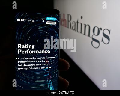 Personne tenant le téléphone portable avec la page Web de l'agence de notation de crédit américaine Fitch Ratings Inc devant le logo de l'entreprise. Concentrez-vous sur le centre de l'écran du téléphone. Banque D'Images
