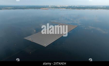 Neuendorf, Allemagne. 15 août 2024. Des modules solaires pour le système photovoltaïque flottant sont en cours d’installation sur la mer Baltique de Cottbus (vue aérienne avec un drone), qui couvrira 18 hectares de la surface du lac (environ un pour cent) avec 51 000 modules solaires une fois achevés. En moyenne, le système peut générer 290000 mégawattheures d'énergie par an. Les corps flottants avec les modules solaires attachés à eux sont reliés au fond du lac par 34 points d'ancrage de sorte que les fluctuations des niveaux d'eau peuvent être compensées. Crédit : Frank Hammerschmidt/dpa/Alamy Live News Banque D'Images