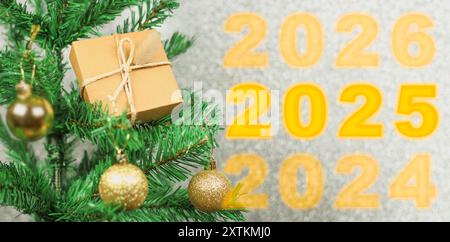 Bonne année 2025 anniversaire. Transition de 2024 à la nouvelle année 2025 image conceptuelle avec ornement de boule dorée sur l'arbre de Noël. Banque D'Images