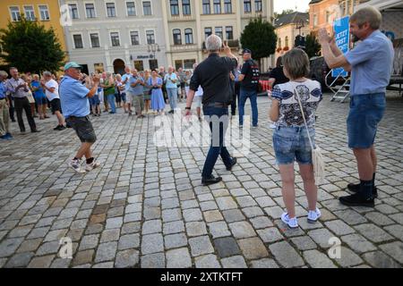 Sebnitz, Allemagne. 15 août 2024. Jürgen Elsässer, rédacteur en chef de 'Compact', entre sur le marché avant le début d'un événement de l'AFD et montre le signe de la victoire. Le chef de la société de médias d'extrême droite voit la décision de la cour en faveur de son journal comme une victoire contre l'ingérence de l'État. Crédit : Robert Michael/dpa/Alamy Live News Banque D'Images