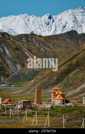 Village d'Abano dans la vallée de Truso, Géorgie : paysage alpin époustouflant avec des sommets enneigés, des prairies colorées et des rivières sinueuses sous un ciel bleu clair Banque D'Images