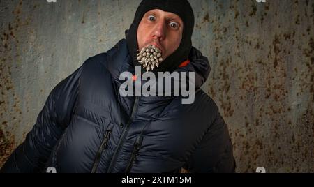 Homme blanc avec veste bleue d'hiver et 29 joints de marijuana dans la bouche Banque D'Images