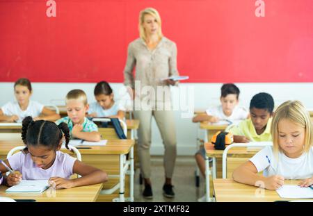 Diligent tweens étudiant en classe avec une enseignante Banque D'Images