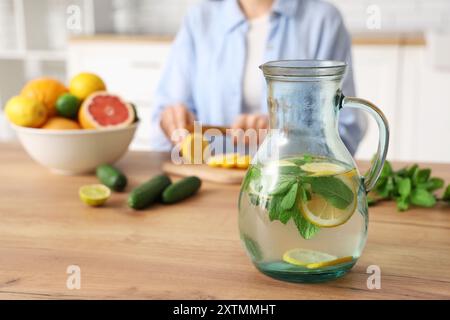 Jeune femme coupant le citron pour préparer l'eau infusée dans la cuisine Banque D'Images