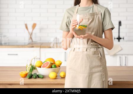 Jeune femme tenant une cruche d'eau infusée avec du citron et de la menthe dans la cuisine Banque D'Images