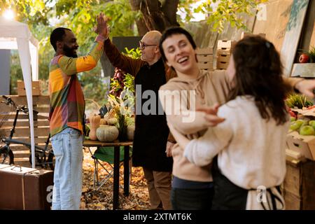 Homme âgé reconnaissant donne au client régulier un haut cinq tout en offrant des fruits et légumes biologiques frais au marché des agriculteurs. Chez greenmarket, les fournisseurs locaux accueillent les clients avec un sourire enthousiaste. Banque D'Images