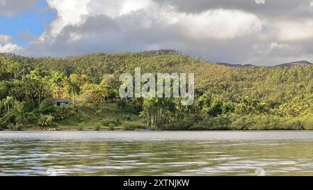 605 tôt le matin, ciel nuageux pour la plupart, naviguant sur l'eau calme de Taco Bay en bateau à rames en regardant la rive sud, le centre d'accueil et la jetée. Baracoa-Cuba Banque D'Images