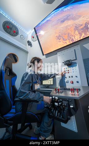 FILED - 15 août 2024, Saxe, Chemnitz : dans le cockpit de la nouvelle capsule spatiale du Centre cosmonaute Sigmund Jähn à Chemnitz, Lena Werner guide à travers l'immensité de l'espace. Après une rénovation complète, la capsule spatiale sera lancée à nouveau pour le 60e anniversaire de l'installation avec des vols spatiaux simulés pour les passagers de tous âges. Samedi (17.08.2024), le Solaris Development Center, sponsor du Cosmonaut Center, organise une célébration d’anniversaire. L'installation pour enfants et jeunes est dédiée aux voyages spatiaux depuis 1964 et apporte l'immensité bey Banque D'Images