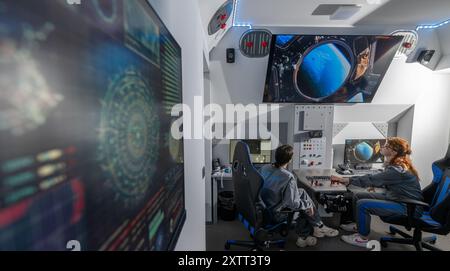 FILED - 15 août 2024, Saxe, Chemnitz : dans le cockpit de la nouvelle capsule spatiale du Centre cosmonaute Sigmund Jähn à Chemnitz, Lena Werner (à gauche) et Zoe Klose manœuvrent dans l'immensité de l'espace. Après une rénovation complète, la capsule spatiale décollera à nouveau avec des vols spatiaux simulés pour les passagers de tous âges pour marquer le 60e anniversaire de l'installation. Samedi (17.08.2024), le Solaris Development Center, sponsor du Cosmonaut Center, organise une célébration d’anniversaire. L'installation pour enfants et jeunes est dédiée aux voyages spatiaux depuis 1964 A. Banque D'Images