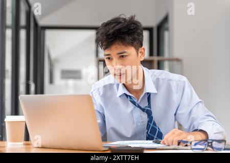 Jeune homme d'affaires fatigué travaillant tard au bureau essayant de respecter la date limite sur son projet Banque D'Images