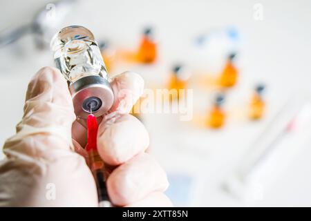 Mpox nouveau vaccin dans les ampoules et les bouteilles, aiguille et les mains des médecins avec gant. Banque D'Images