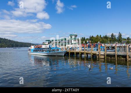 Les touristes attendent des bateaux de plaisance sur la rive de Bowness-on-Windermere dans le parc national du Lake District en Angleterre par une journée d'été ensoleillée. Banque D'Images