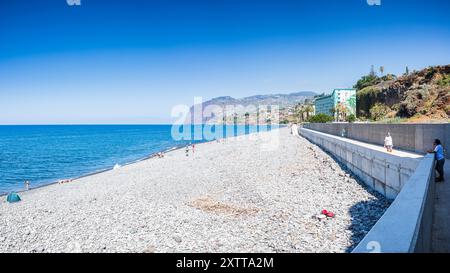 Un panorama multi-image de Praia Formosa avec des bains de soleil parsemés sur les galets à Funchal, Madère vu le 4 août 2024. Banque D'Images