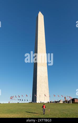 Washington DC, USA - 10 octobre 2022 : le Washington Monument se dresse haut contre un ciel bleu clair, symbole de la démocratie américaine. Un homme fait voler un cerf-volant Banque D'Images