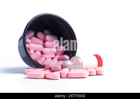 Pilules roses et bouteille de vaccin renversé de boîte en plastique noir sur fond blanc avec espace de copie Banque D'Images