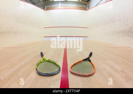 Court de squash vide et raquettes sur le plancher en bois. Vue large et basse, pas de personnes. Banque D'Images