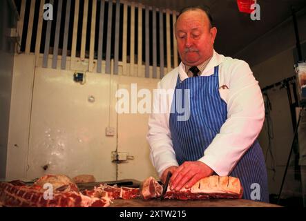 Le boucher gallois Tom Price dans sa boucherie locale traditionnelle d'Oxford Street. Vêtu de vêtements de travail, il a été boucher toute sa vie. Mountain Ash, Glamorgan, pays de Galles du Sud des années 1998 1990 Royaume-Uni HOMER SYKES Banque D'Images