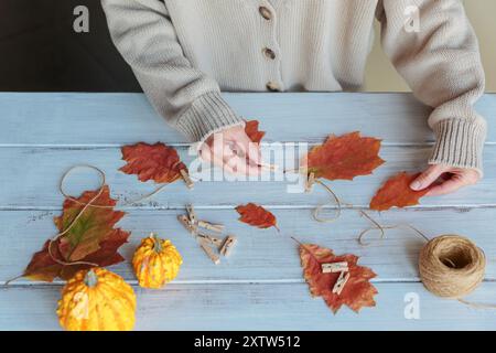 Guirlande maison de feuilles d'automne colorées avec des mains de femmes Banque D'Images