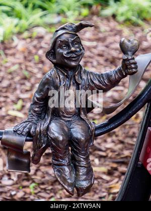 Wroclaw, Pologne - septembre 2022 : nain magique de Wrocław avec un cœur dans la main assis sur le banc. Petites figures en bronze de nains dans les rues o Banque D'Images