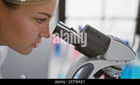 Chercheuse caucasienne focalisée utilisant le microscope en laboratoire Banque D'Images