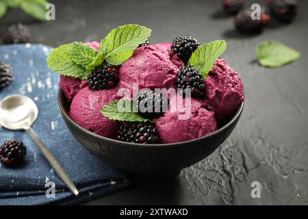 Délicieux sorbet aux mûres, baies fraîches et menthe dans un bol servi sur une table texturée grise Banque D'Images